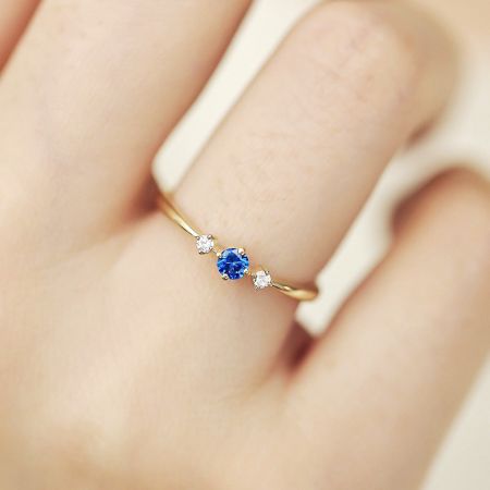 Bagues en pierre de naissance de septembre en zirconia cubique plaquées or en argent sterling 925 en gros - Gros plan d'une bague plaquée or en argent sterling 925 avec une zirconia cubique bleue centrale, la pierre de naissance de septembre, avec de plus petites pierres blanches de chaque côté.