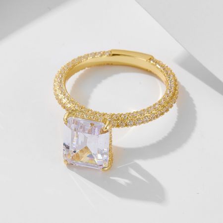 Primer plano detallado del anillo de cóctel CZ con corte cojín, con su brillante piedra central y banda de oro incrustada.