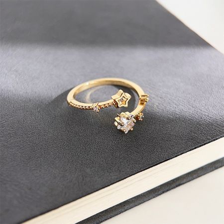 Vista detallada de un anillo de oro con una piedra preciosa clara y un delicado acento de estrella.
