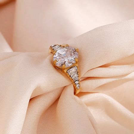 Scatto di prodotto di lusso dell'anello regolabile in zirconia bianca con accenti a baguette, appoggiato su un morbido tessuto di satin pesca.