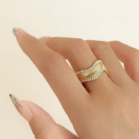 Vue détaillée d'une bague en or avec un design ondulé et des accents en zircon ressemblant à des diamants.