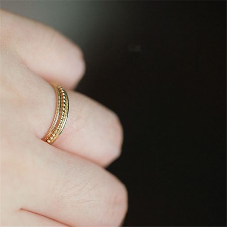 Gros plan sur une bague empilable en or de l'ensemble, présentant un design délicat à pois.
