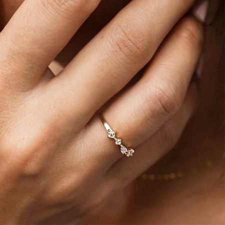 Nahaufnahme des vier-Zirkon-Stapelrings in Weiß, der an einem Finger getragen wird.