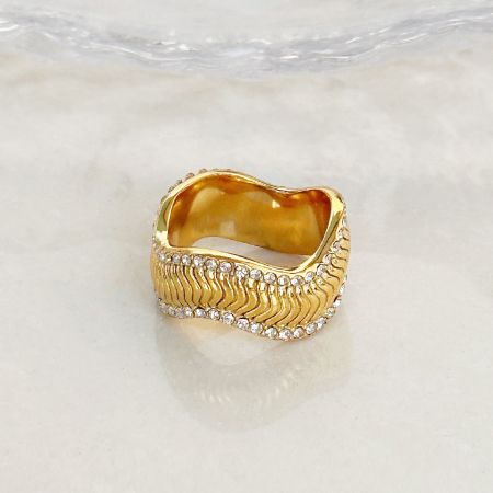 Gros plan d'une bague en or avec des pierres précieuses claires de l'ensemble de bagues ondulées.