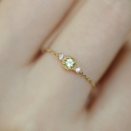 En kvinnas hand som bär den justerbara olivine zirkonia födelsestenringen, som visar dess eleganta passform.
