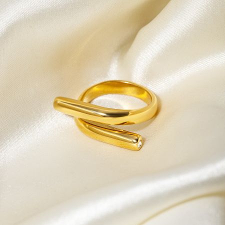 Vista detalhada de um único anel dourado com um design de barra cruzada do conjunto.