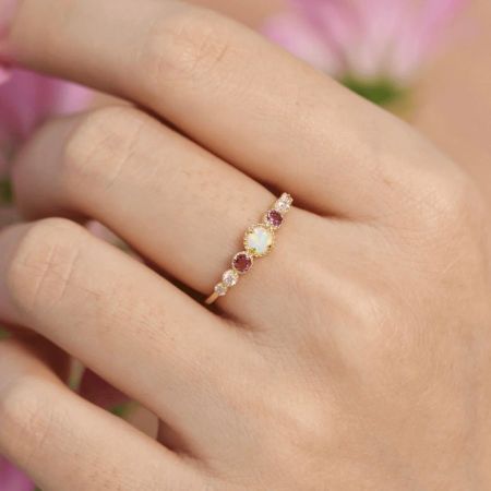 Nahaufnahme des Opal- und Zirkonrings, der an einem Finger getragen wird und seinen brillanten Glanz zeigt.