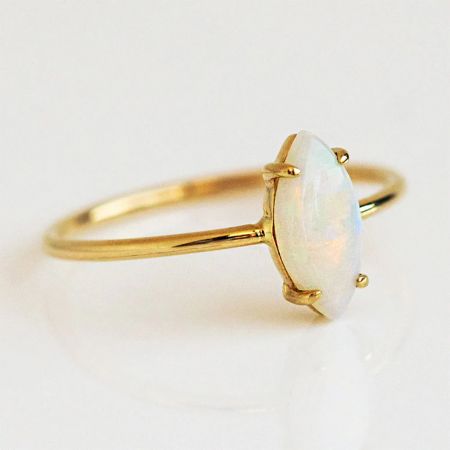 Set di 5 anelli solitari in opale in argento sterling 925 - Primo piano di un anello impilabile in argento sterling 925 con una pietra di opale ovale lucente, montato su una delicata fascia con finitura dorata.