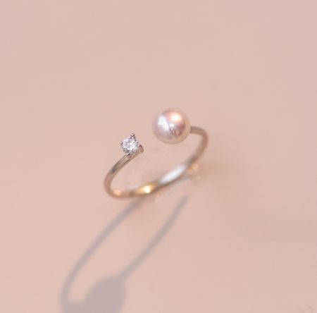 Anello di apertura in argento sterling 925 con perla - Un primo piano dell'anello di apertura in argento sterling 925 con perla, che mostra la sua placcatura in oro, la perla centrale e la pietra in zirconia cubica accentata su uno sfondo bianco.