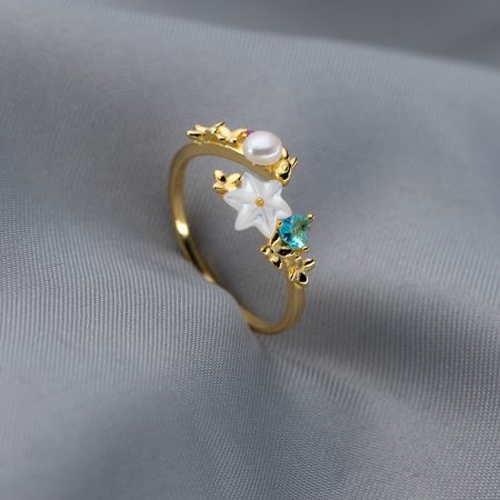 真珠、白い花、淡い青い宝石を展示した調整可能な金の指輪。