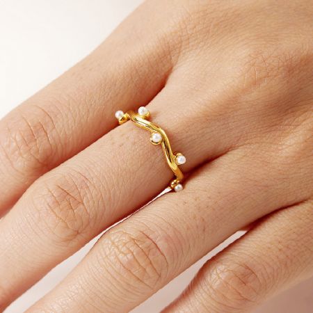 Roestvrijstalen vergulde onregelmatige golf tak parel open ringen set van 5. - De hand van een vrouw die de vergulde roestvrijstalen ring met parelaccenten uit de 5-delige set draagt.