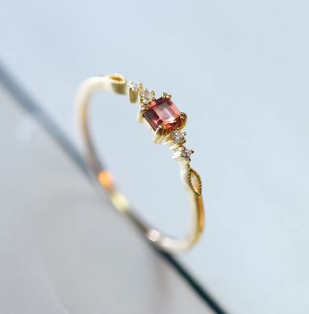 Angled view of the gold-plated sterling silver ring, displaying the elegant setting of the pinkish-red gemstone.