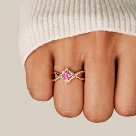 Vista en ángulo del elegante anillo de zirconia rosa que muestra su diseño de banda entrelazada.