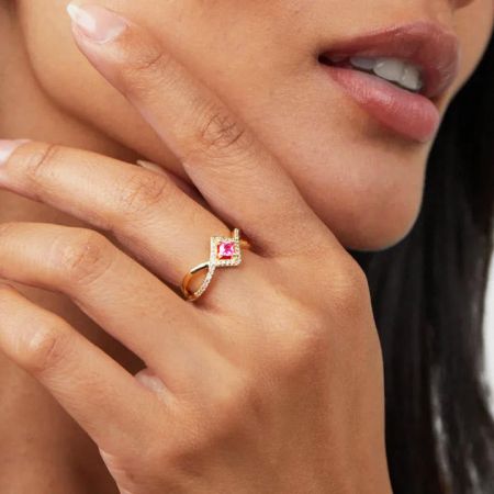 Toma de producto desde arriba del anillo de piedra preciosa rosa brillante sobre un fondo blanco.