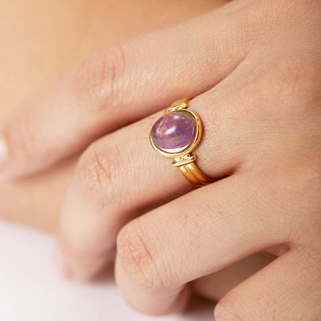 Zijprofiel van de goudafgewerkte amethist ring op een hand