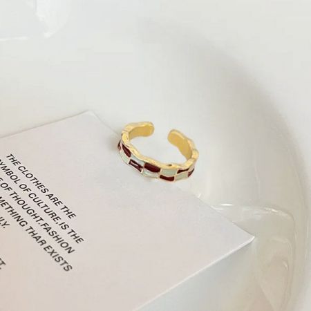 A stylish gold-plated enamel ring resting on a book, showcasing its detailed craftsmanship.
