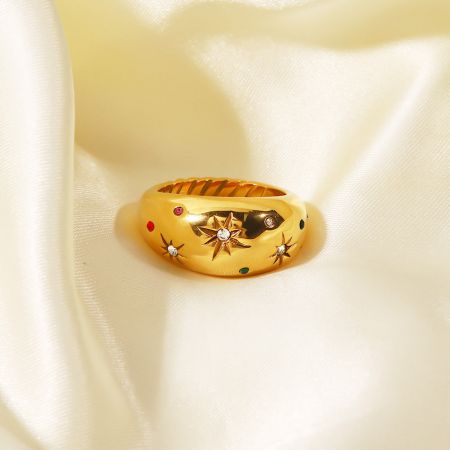 Primer plano del anillo de estrella grueso con piedras de múltiples colores sobre un fondo de satén.