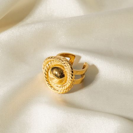 テクスチャーのある縁と滑らかな中央の球体を持つゴールドリングの詳細ビュー。