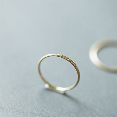 Bande de bague fine empilable minimaliste en argent sterling 925 - Une bague empilable minimaliste en argent sterling 925 avec une finition en or texturé, montrée sur le côté pour détailler l'artisanat.
