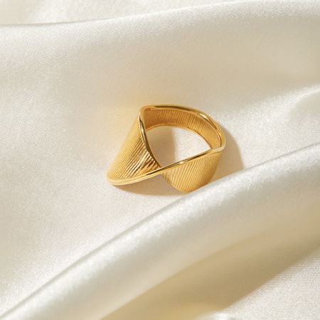 Une élégante bague en or texturée de la collection, reposant sur un doux tissu en satin.
