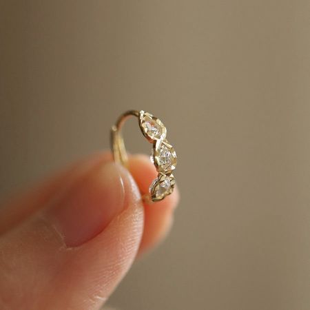Detailed view of the triple teardrop CZ huggie earring in 14K gold plating.