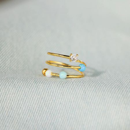 Ein Produktfoto des vergoldeten Starlit Ocean Rings, das das Triple-Band-Design mit Opal- und Zirkonsteinen hervorhebt.