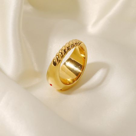 Un anillo dorado de diseño retorcido único de la colección, colocado sobre un fondo de satén blanco.
