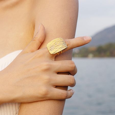 Roestvrijstalen gouden vintage geometrische chunky open ringen - Set van 5 - Een close-up van een goudkleurige roestvrijstalen ring met een golvend, getextureerd ontwerp, onderdeel van een vintage geometrische set.