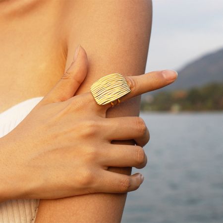 Close-up van de ring met golvende textuur van roestvrij staal in een gouden afwerking.