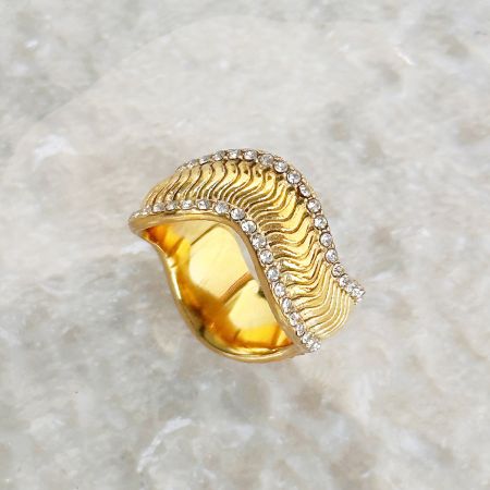 Mise en valeur du motif ondulé unique et des embellissements en zircon sur la bague en or.