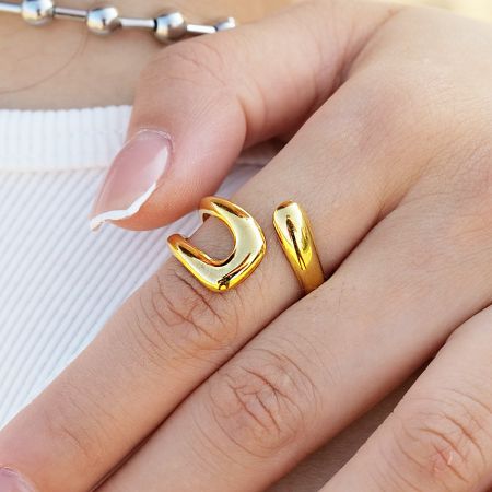 Verstelbare ringen van roestvrij staal met slang, holle open kruis - Set van 5 - De hand van een model met een set van verstelbare ringen van roestvrij staal met gouden afwerking, inclusief slang- en open-kruisontwerpen, gecombineerd met een zilveren armband.