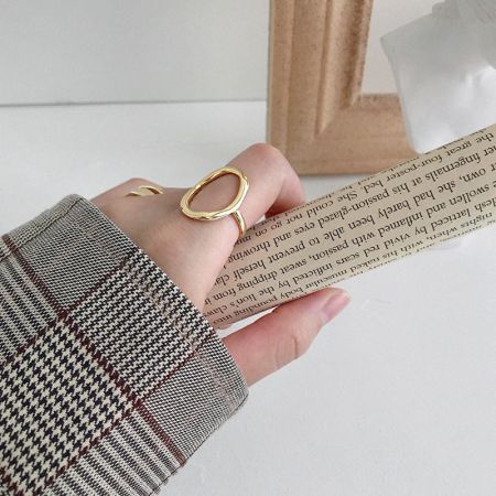 Lifestyle view of the 18K gold plated oval open rings worn on a model's hand.