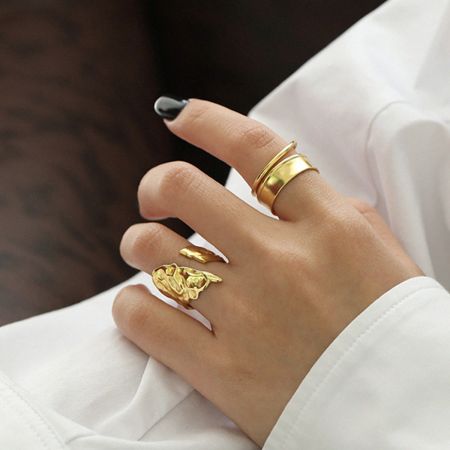 金のダブルバンドリングを着用したモデルのクローズアップで、その彫刻的でトレンディなデザインを強調しています。
