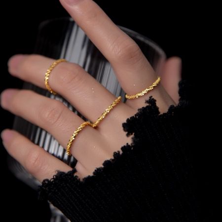 La mano del modelo mostrando la versión chapada en oro del anillo de cadena minimalista.