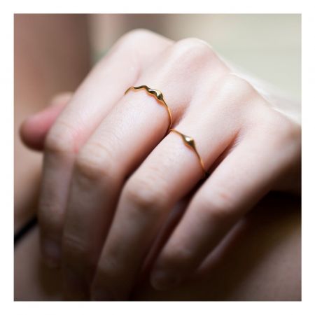 De hand van het model met meerdere gouden golvende ringen om een gestapeld uiterlijk te demonstreren.
