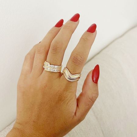 Deux bagues en or de l'ensemble portées sur une main avec des ongles rouges, pour un contexte de style de vie.