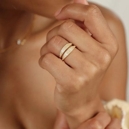 Lifestyle-Bild, das die goldenen Pavé-Signet-Ringe zeigt, die auf dem Finger einer Frau gestapelt sind.