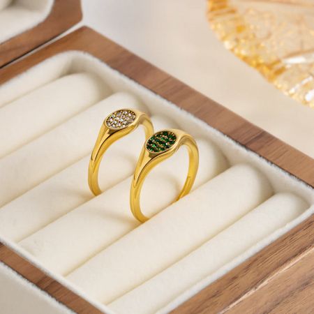 De groene en witte zircon signetringen elegant tentoongesteld in een houten sieradenkist.