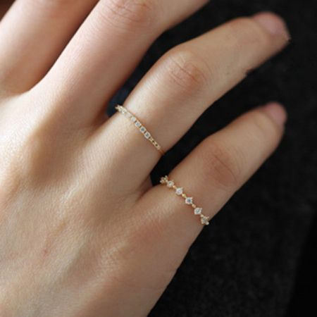 Anelli in zirconio scintillante in argento sterling 925 (Set di 5) - La mano di una donna che indossa elegantemente un set di anelli in zirconio scintillante in argento sterling 925 con finitura dorata, mostrando il loro design impilabile.
