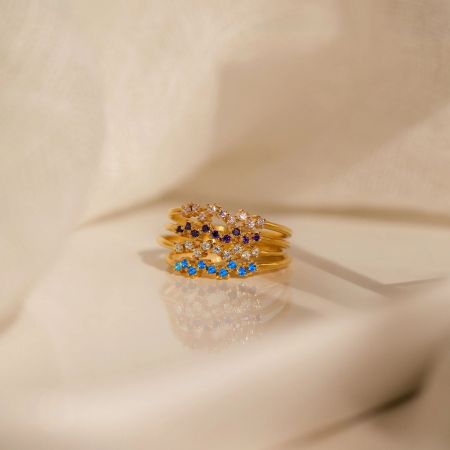 A set of four stackable sterling silver birthstone rings with a gold finish, featuring various colored CZ stones.
