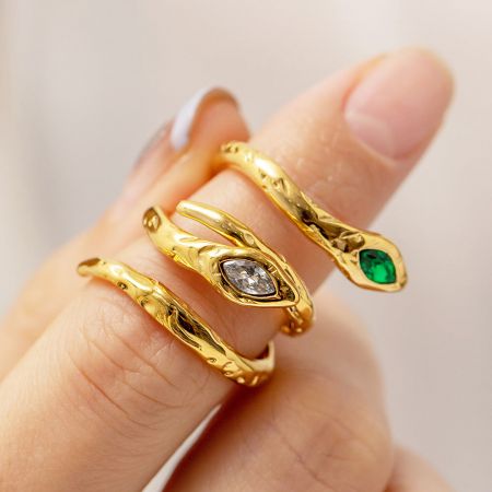 Trois bagues en or uniques du set, mettant en valeur les designs complexes et les pierres précieuses scintillantes.