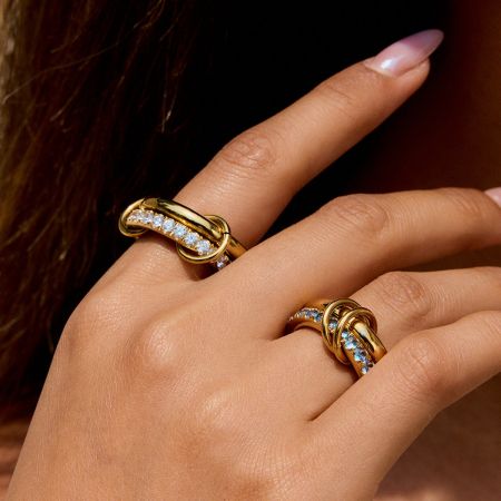 Gouden PVD-geplateerde roestvrijstalen zircon ringenset van 5 - De hand van een vrouw die elegant de Gouden PVD-geplateerde roestvrijstalen zircon ringenset draagt, met twee van de stapelbare ringen met schitterende witte edelstenen.