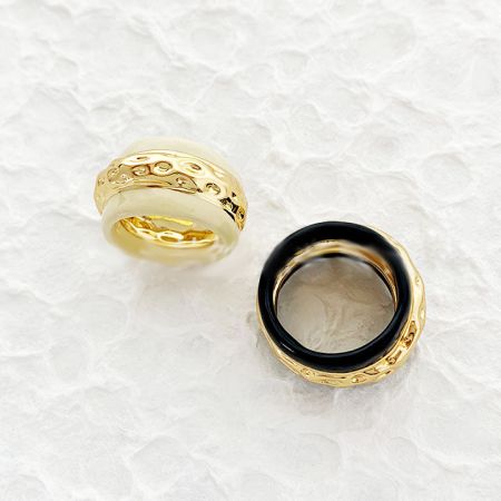 Close-up view of two gold-accented enamel rings with intricate vintage designs.
