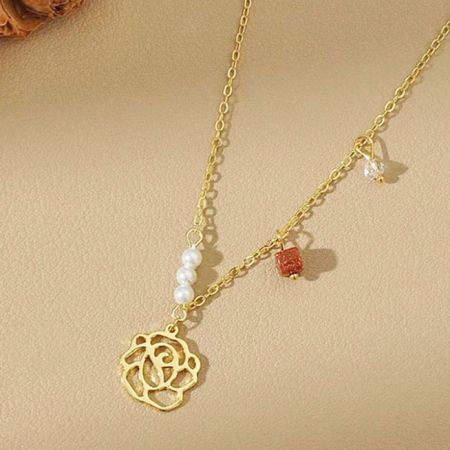 Een vergulde ketting uit de set met een rozenhanger en verschillende delicate bedels.