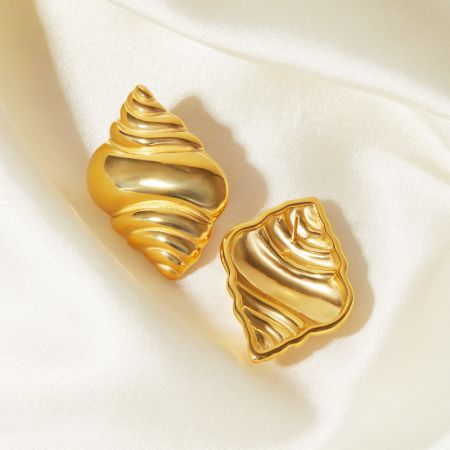 Gros plan sur les boucles d'oreilles en or en forme de coquillage mettant en valeur leur texture détaillée.