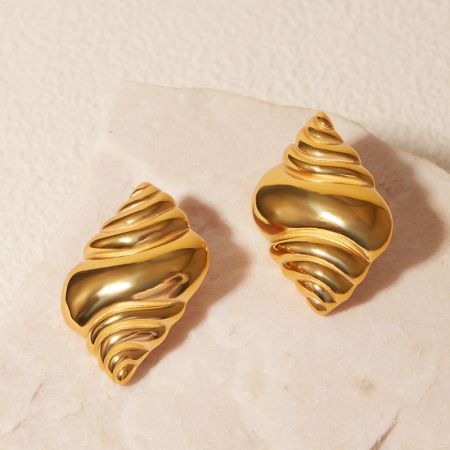 Une autre vue des élégantes boucles d'oreilles en or en forme de coquillage sur un fond neutre.