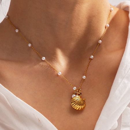 Nahaufnahme der goldenen Muschel-Anhänger-Halskette mit eleganten Perlenakzenten an der Kette.
