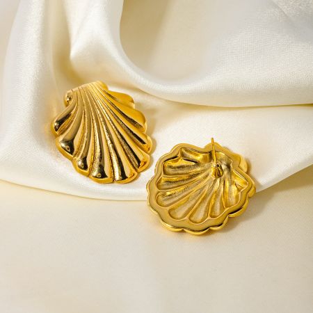 A pair of gold scallop shell stud earrings displayed elegantly on a white satin background.