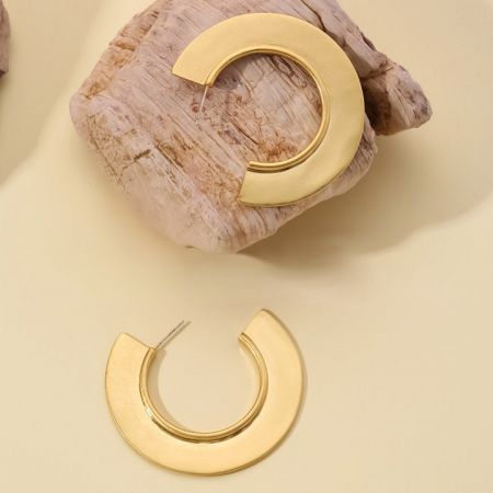 Detailed view of the unique semi-circular design of the gold brass hoop earrings.
