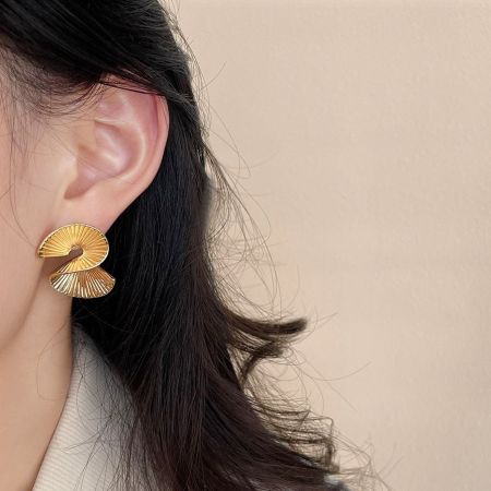 Modello che indossa l'orecchino geometrico irregolare in oro, che mostra il suo stile moderno.